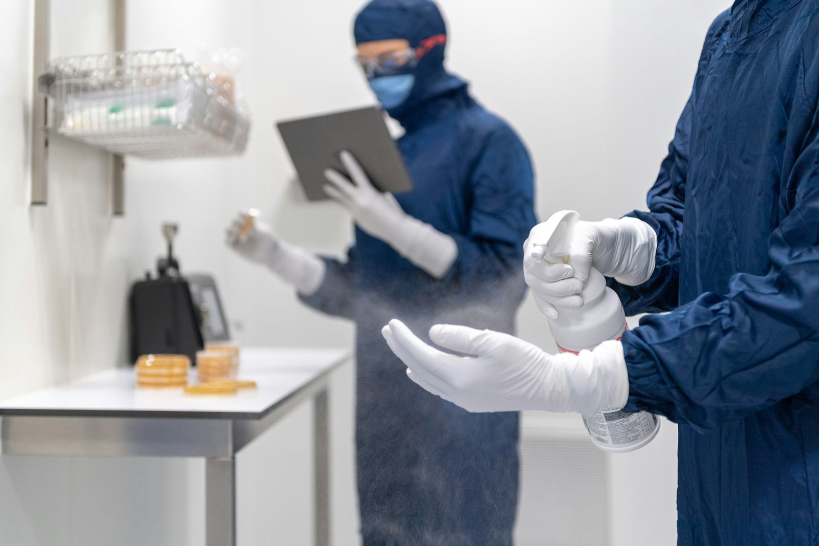 Dos operarios con guantes y mascarilla desinfectan una superficie